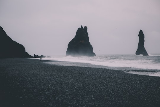 grayscale photo of beach with waves during daytime in Reynisdrangar Iceland