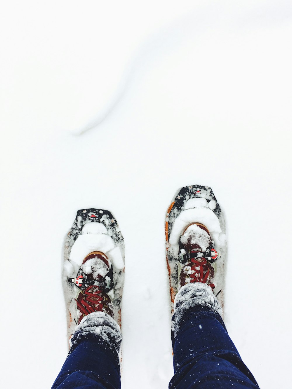 ブルージーンズを履いた人が雪の上に立つ