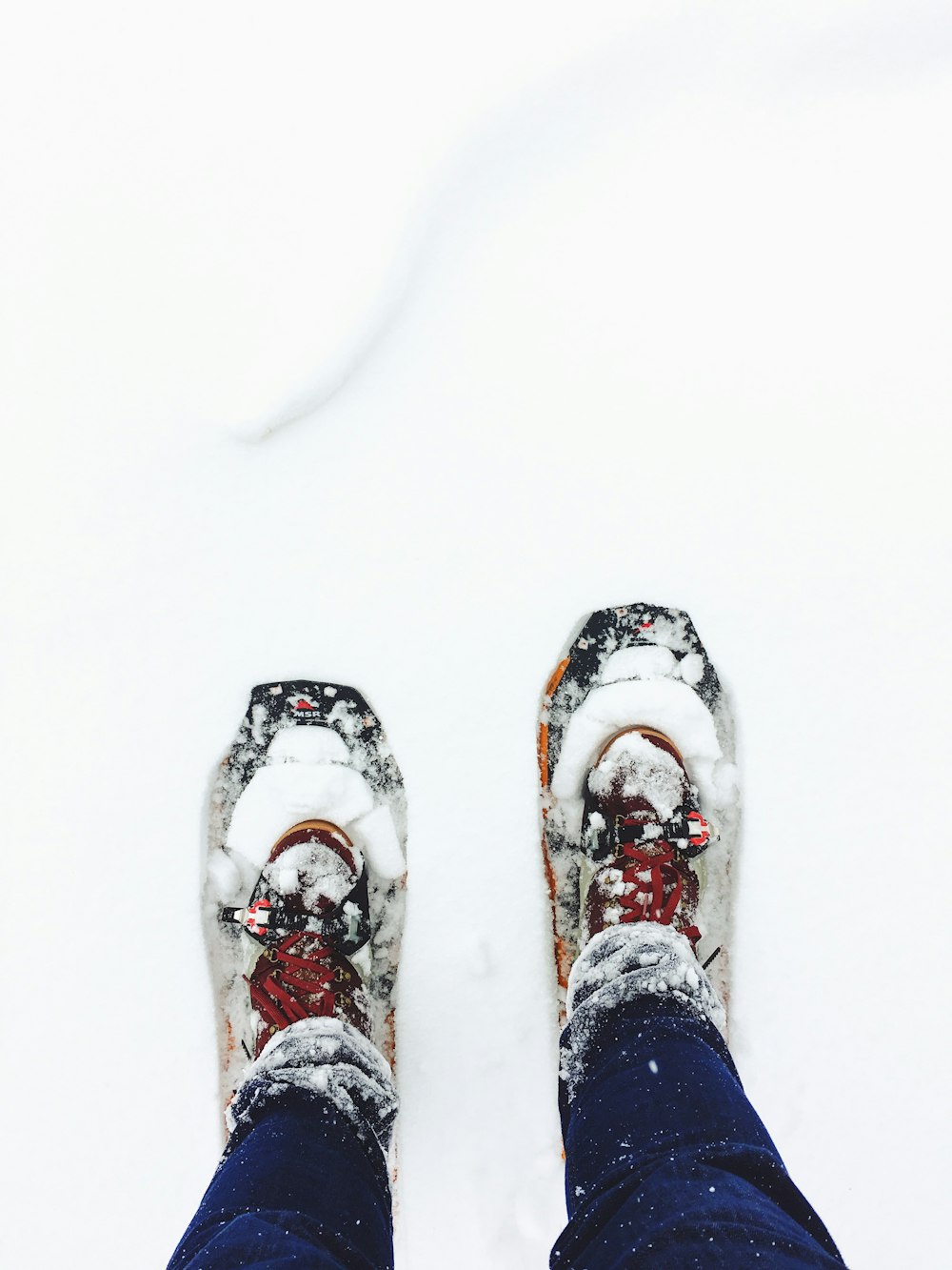 person wearing blue jeans standing on snow