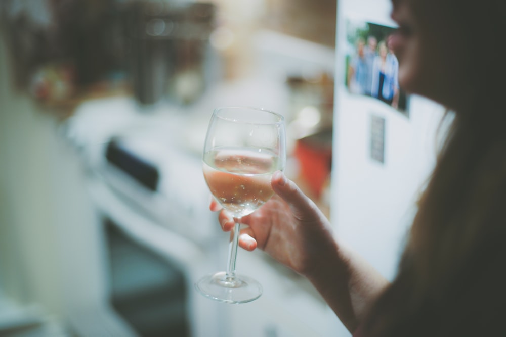 A woman holding a glass of white wine.