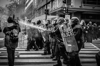 grayscale photo of police riot team on pedestrian lane
