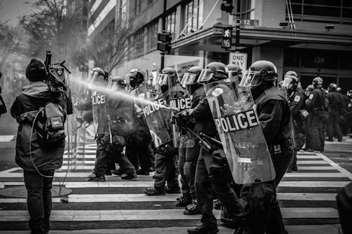 grayscale photo of police riot team on pedestrian lane