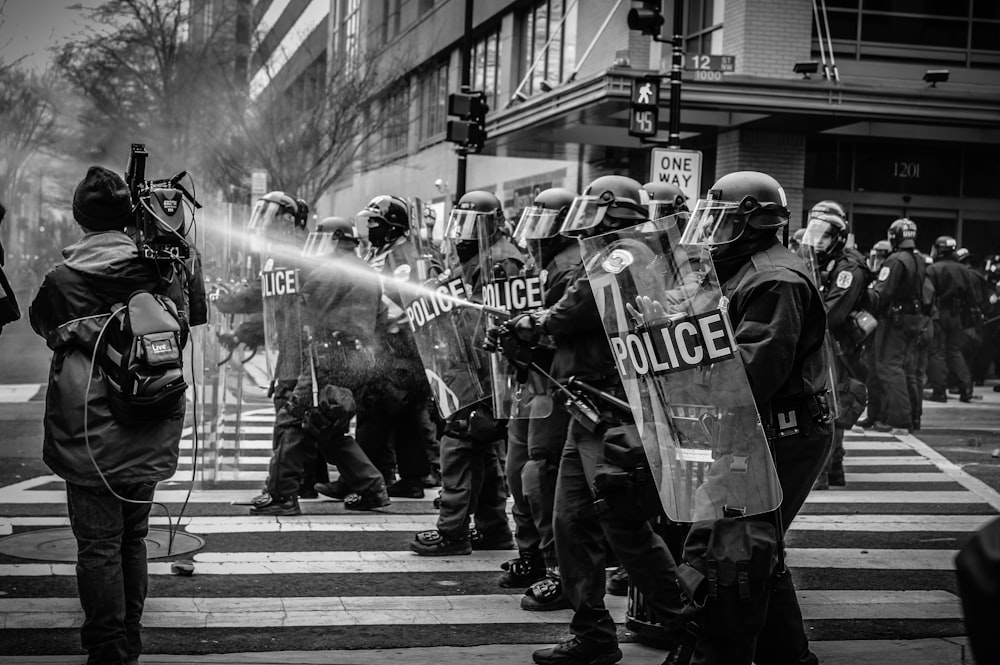 Foto in scala di grigi della squadra antisommossa della polizia sulla corsia pedonale