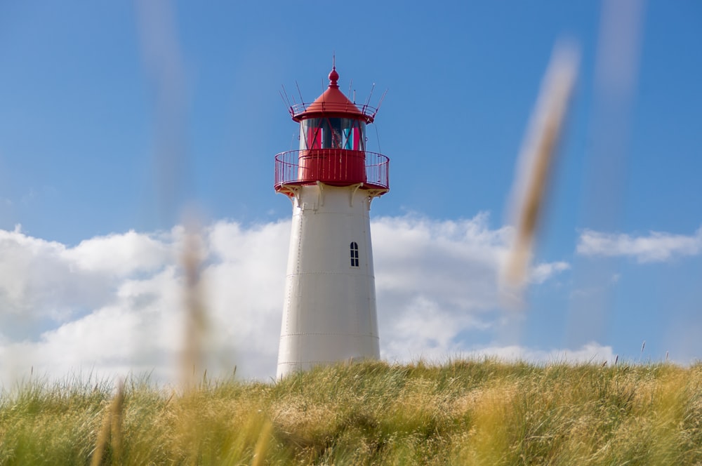 faro blanco y rojo bajo foto de cielo nublado azul y blanco