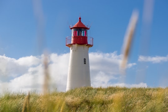 white and red lighthouse under blue and white cloudy sky photo in Leuchtturm List-West Germany