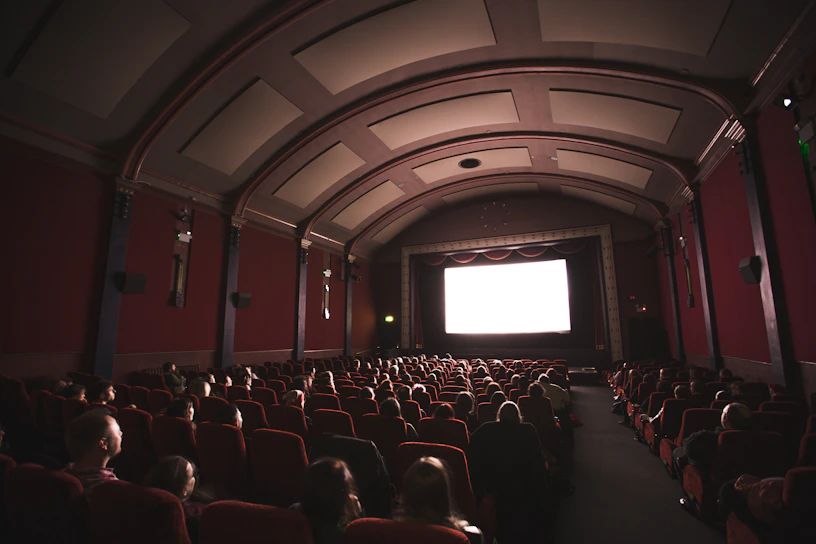 A vibrant movie theater screen showing a classic film scene with an enthusiastic audience.