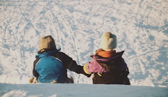 Kids dressed in playful winter jackets against a snowy hill station scene.