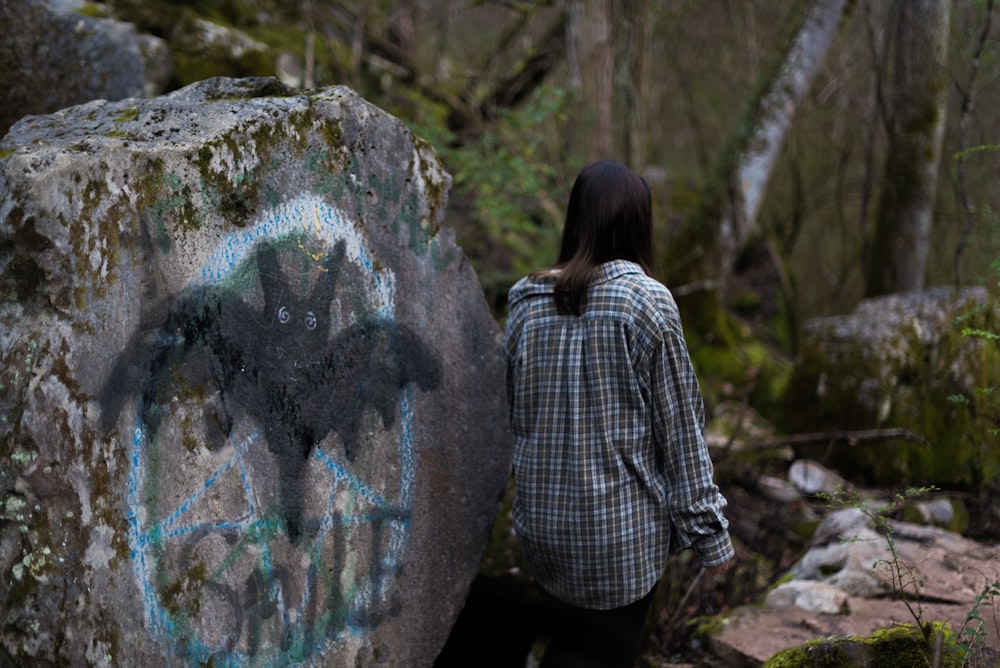 Frau schwarz-weiß kariertes Langarmhemd neben grauem Felsen