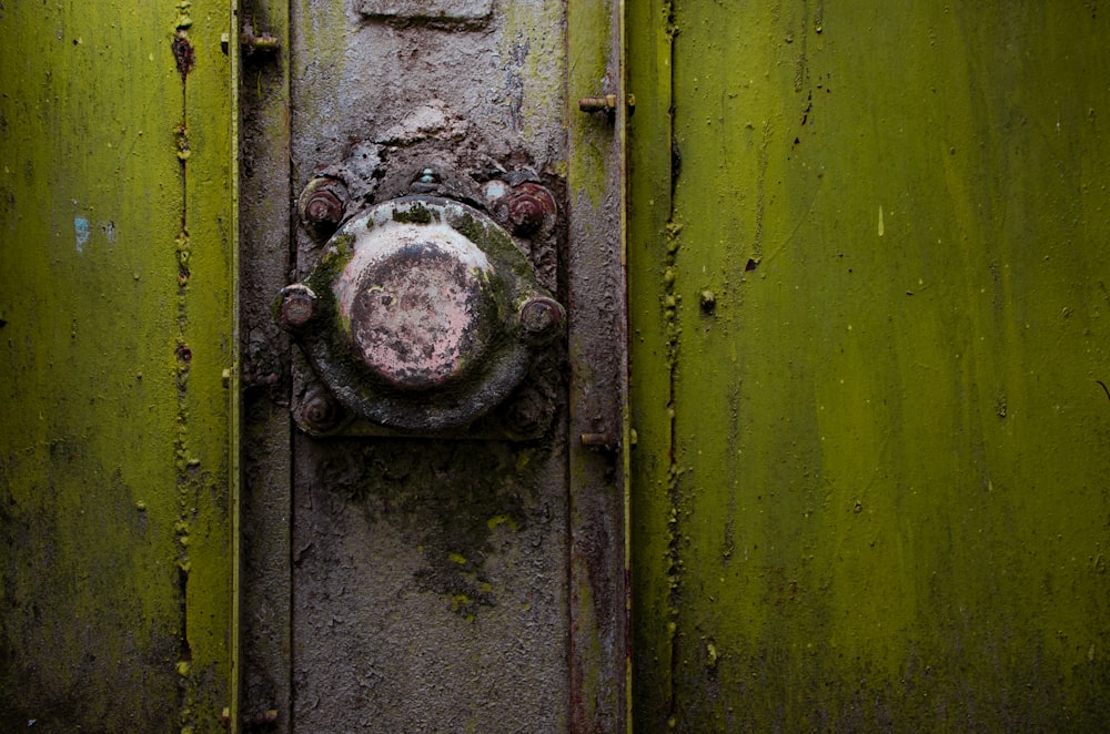 A close-up of a rusty metal knob on a green strongbox