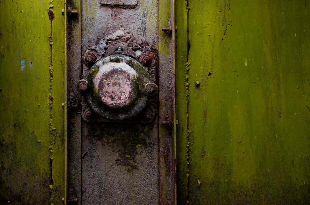 A close-up of a rusty metal knob on a green strongbox