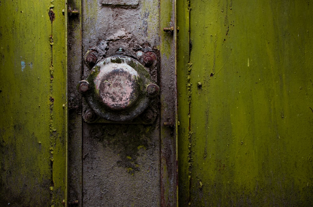 Um close-up de um botão de metal enferrujado em uma caixa forte verde