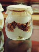 Sunlit artisanal yogurt jars with natural ingredients displayed on a white linen cloth.