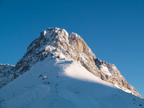 A crisp, sunlit mountain peak with a clear blue sky backdrop, capturing the essence of Liberty Peak.