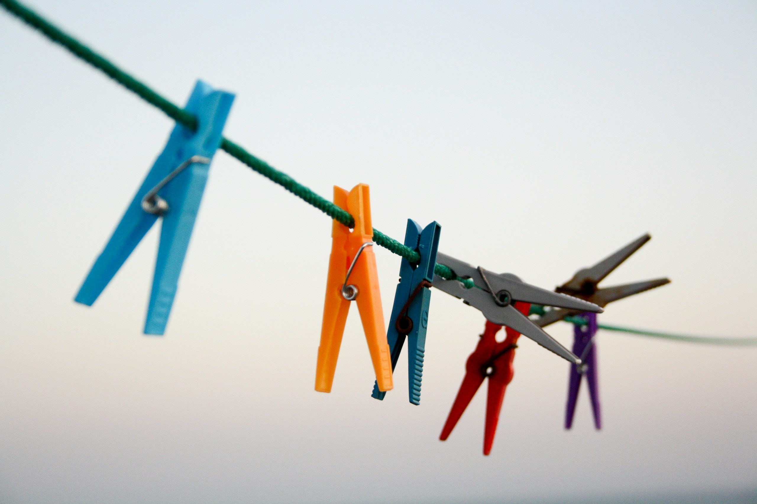 seven assorted-color clothes pegs hanging on rope