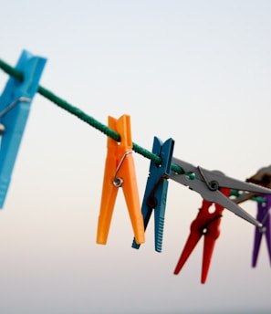 seven assorted-color clothes pegs hanging on rope \