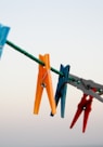 seven assorted-color clothes pegs hanging on rope \