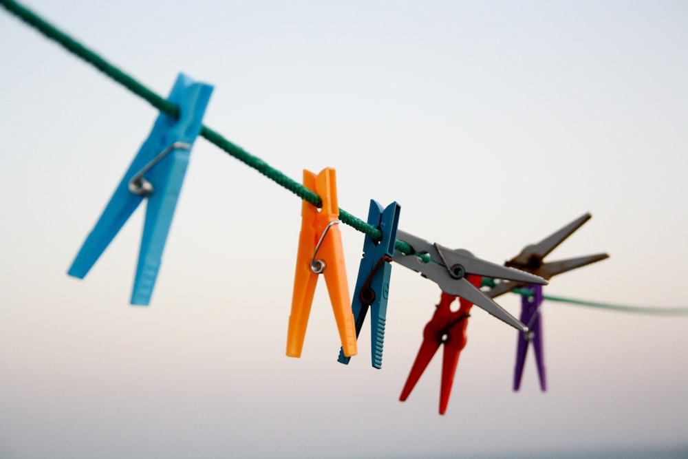 sieben verschiedenfarbige Wäscheklammern hängen am Seil \
