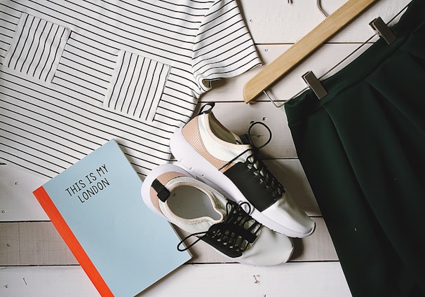 pair of white-and-black low-top sneakers near black skirt on brown clothes hanger top view photography