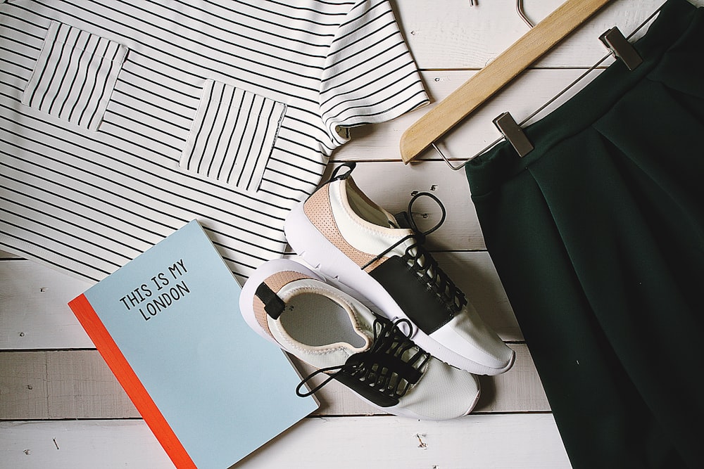 pair of white-and-black low-top sneakers near black skirt on brown clothes hanger top view photography