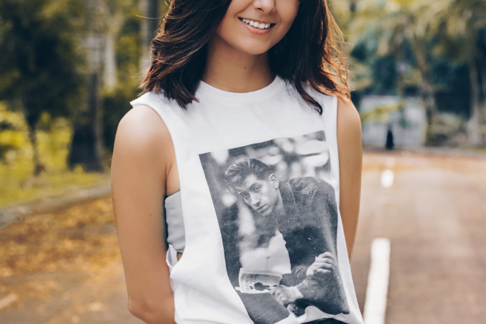 woman wearing white sleeveless top standing on asphalt road during daytime