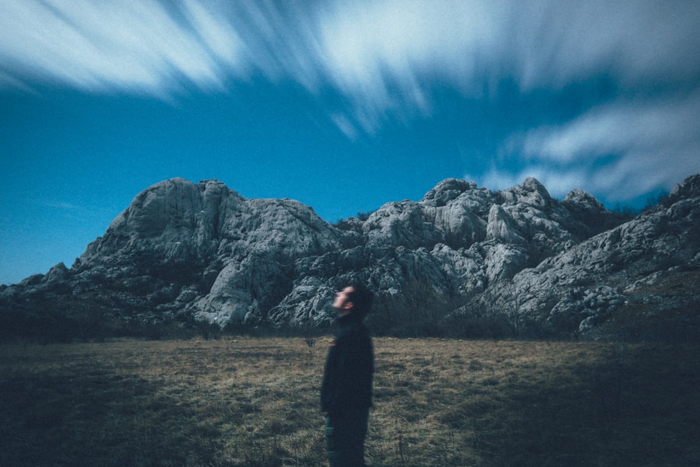 man looking up the sky located across the rock formation