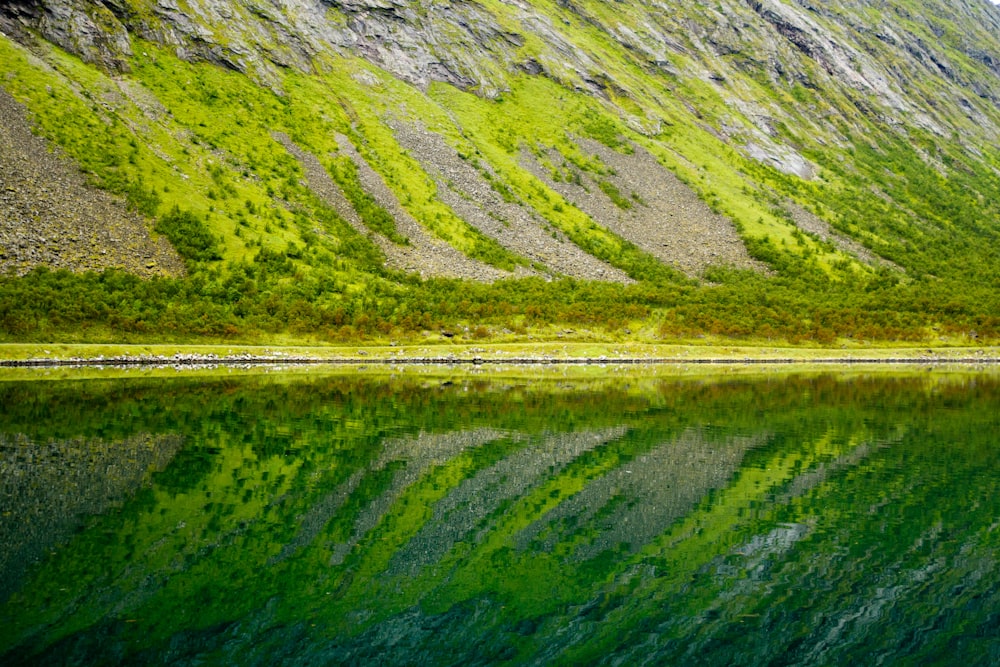 Spiegelung von abschüssigem Land auf stillem Wasser