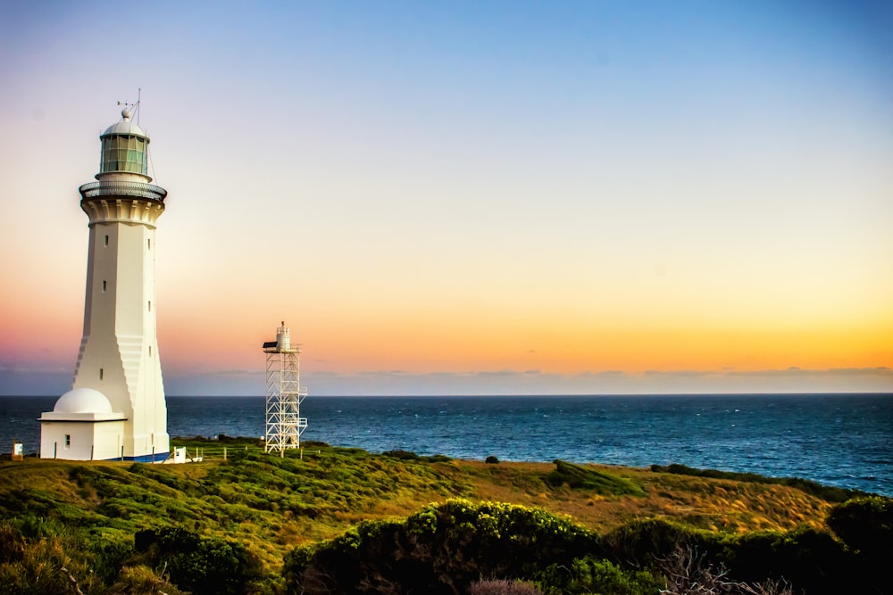 white concrete lighthouse near seashore at daytime