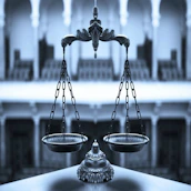 Black and white close-up of legal scales balanced on a polished desk.