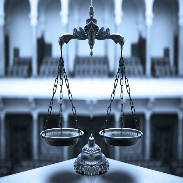 Close-up of a golden justice scale balanced on a white marble surface.