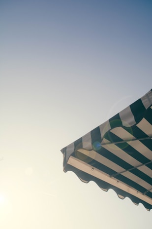 Large striped awning in blue and white protecting a storefront from the sun.