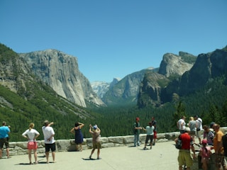 A group of happy travelers admiring a stunning mountain vista under a clear blue sky.