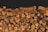 A large pile of neatly stacked, cut firewood with visible bark and varying sizes and textures of logs.