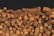 A large pile of neatly stacked, cut firewood with visible bark and varying sizes and textures of logs.