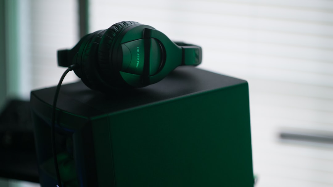 black headphones above black box, Music equipment in green light