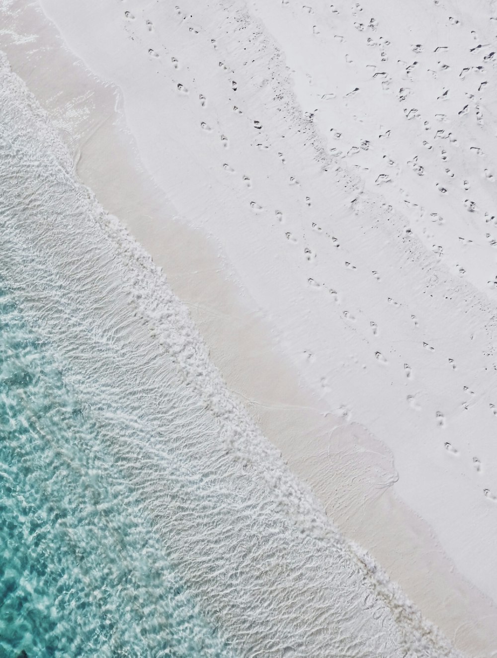 Fotografía aérea de la orilla del mar de arena blanca y la playa de agua verde