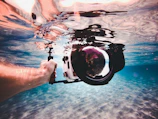 person holding white and black underwater camera