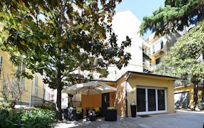 A cozy corner of the property showing a small shaded seating area among lush green plants