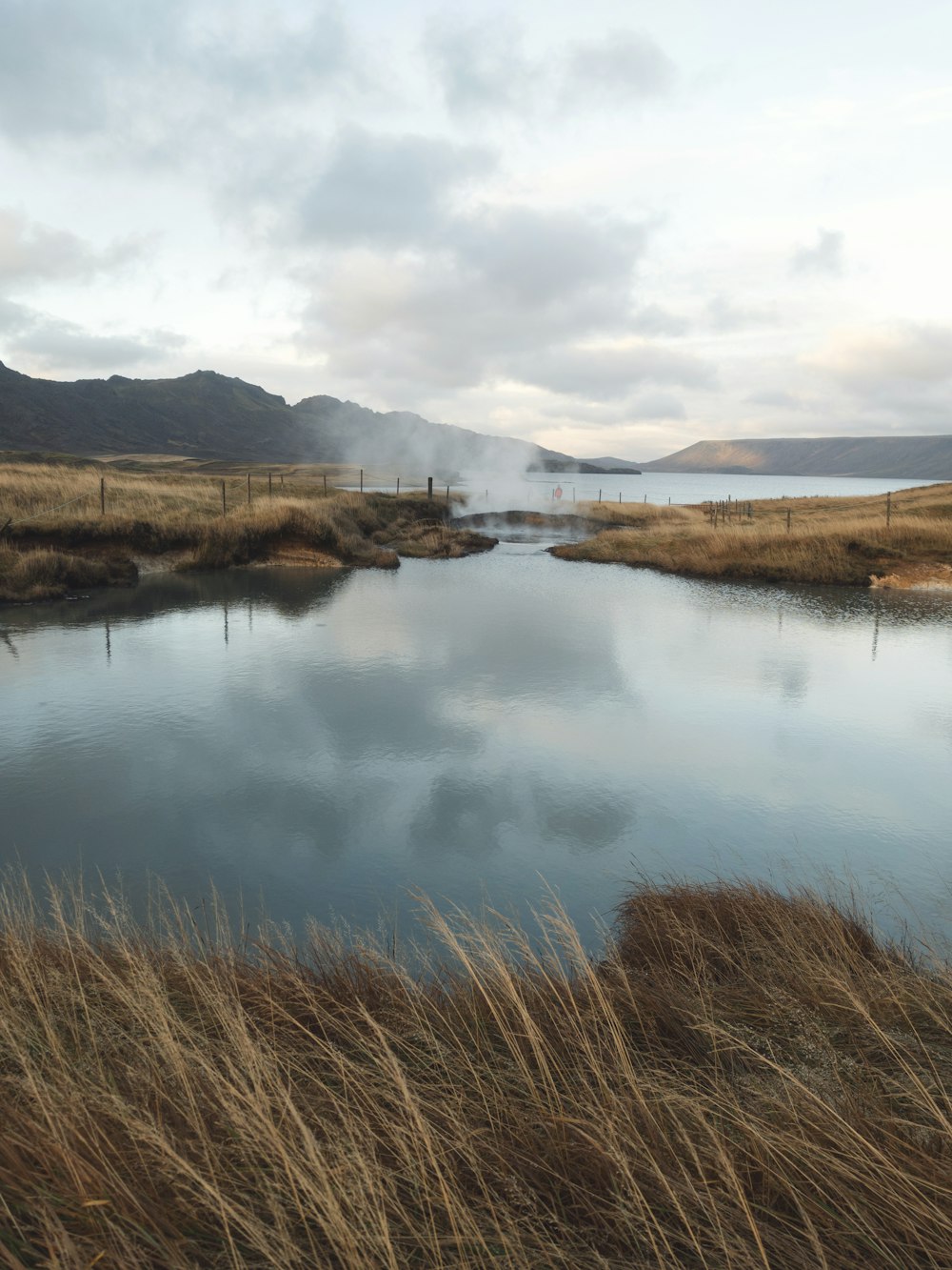 lake near mountain under cloudy sky at daytime