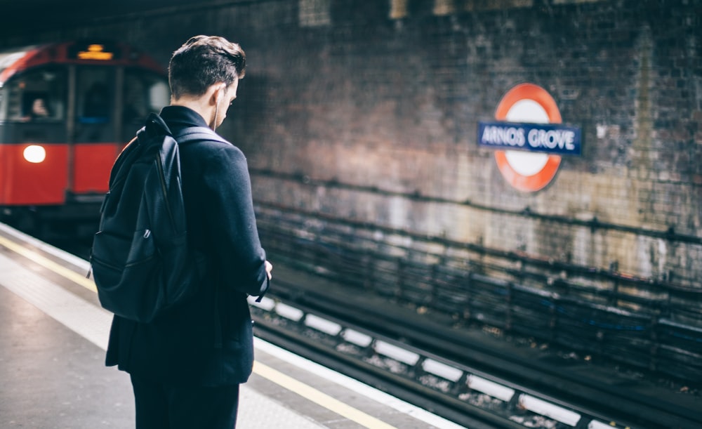 man with backpack standing on train station