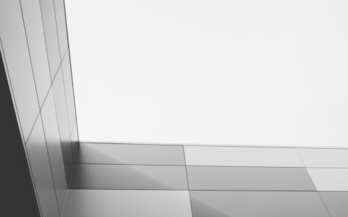 A minimalist architectural structure with clean lines and panels that create geometric shapes. The image features a sleek, modern design with a color palette of grays and whites, contributing to a sense of elegance and simplicity.