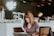 woman sitting on brown wooden chair while using silver laptop computer in room