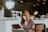 woman sitting on brown wooden chair while using silver laptop computer in room