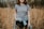woman wearing gray crew-neck t-shirt with jacket wrap around her waist standing on brown grass field during daytime