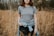 woman wearing gray crew-neck t-shirt with jacket wrap around her waist standing on brown grass field during daytime