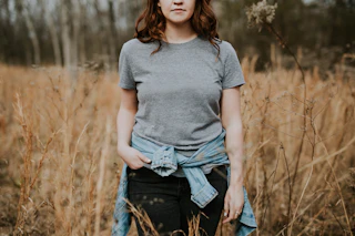 Woman in a grey cotton tee with a denim shirt tied at the waist