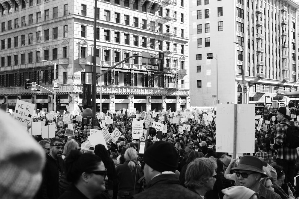 Fotografía en escala de grises de personas protestando frente a un edificio de hormigón