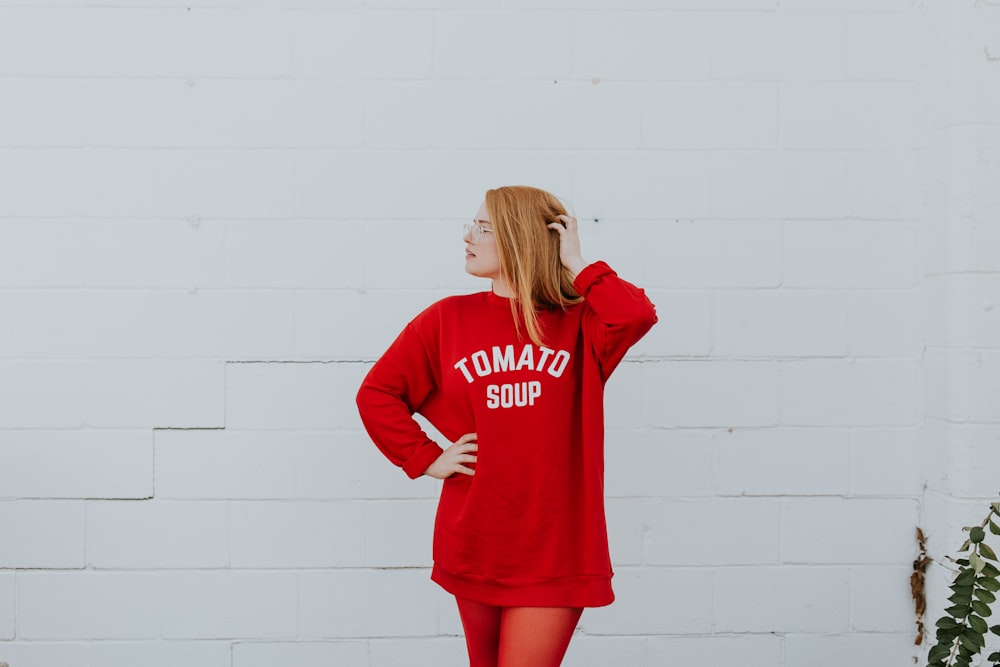 woman wearing red long-sleeved shirt standing near white painted wall