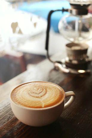 A close-up of a freshly brewed coffee cup with latte art on a wooden table.
