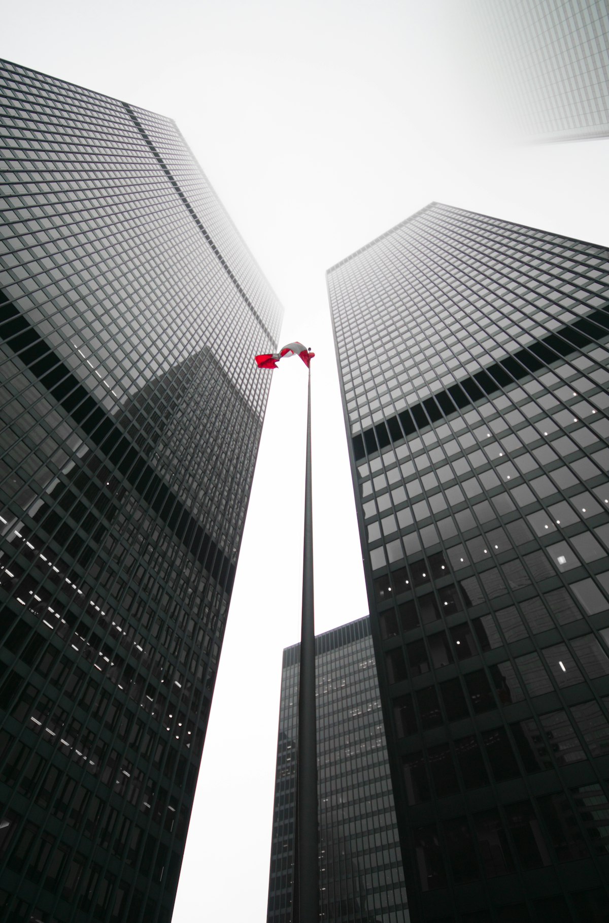 Ultra-wide angle photograph looking up at buildings with a flag between skyscrapers