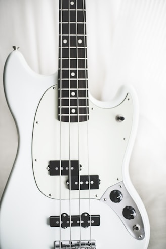 white and black electric bass guitar on white surface
